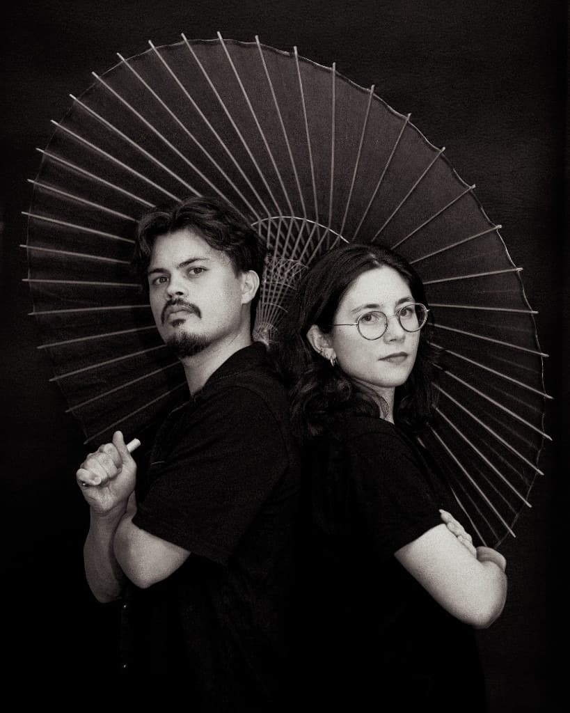 Les fondateurs d'Uncommon, photographiés en noir et blanc sous un parapluie ouvert